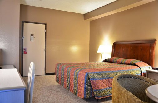 Cozy hotel room at Hotel PG, equipped with a bed, desk, and television for a pleasant stay.