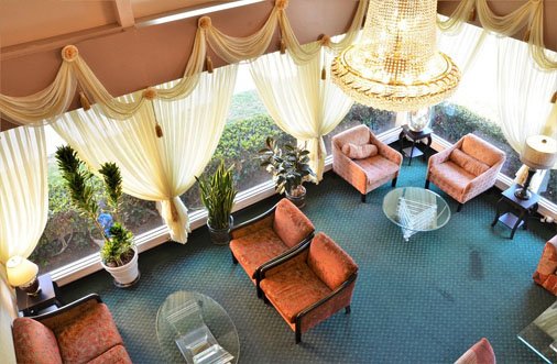 Hotel PG's lobby showcases a beautiful chandelier and comfortable couches, creating a welcoming atmosphere for visitors.