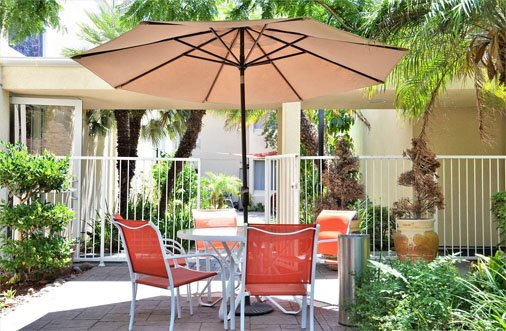 Outdoor seating area at Hotel PG with a table and chairs under an umbrella, ideal for enjoying meals in comfort.
