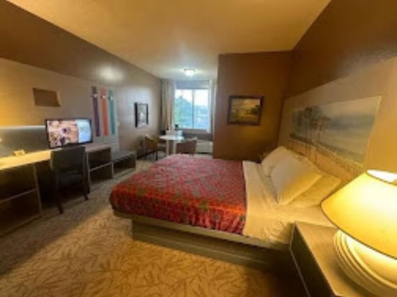 A well-appointed motel room at Hotel PG, complete with a bed, chair, and television for guest comfort.