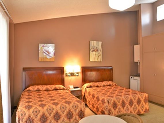 Interior view of a Hotel PG room showcasing two beds and a television, ideal for guests seeking a cozy stay.